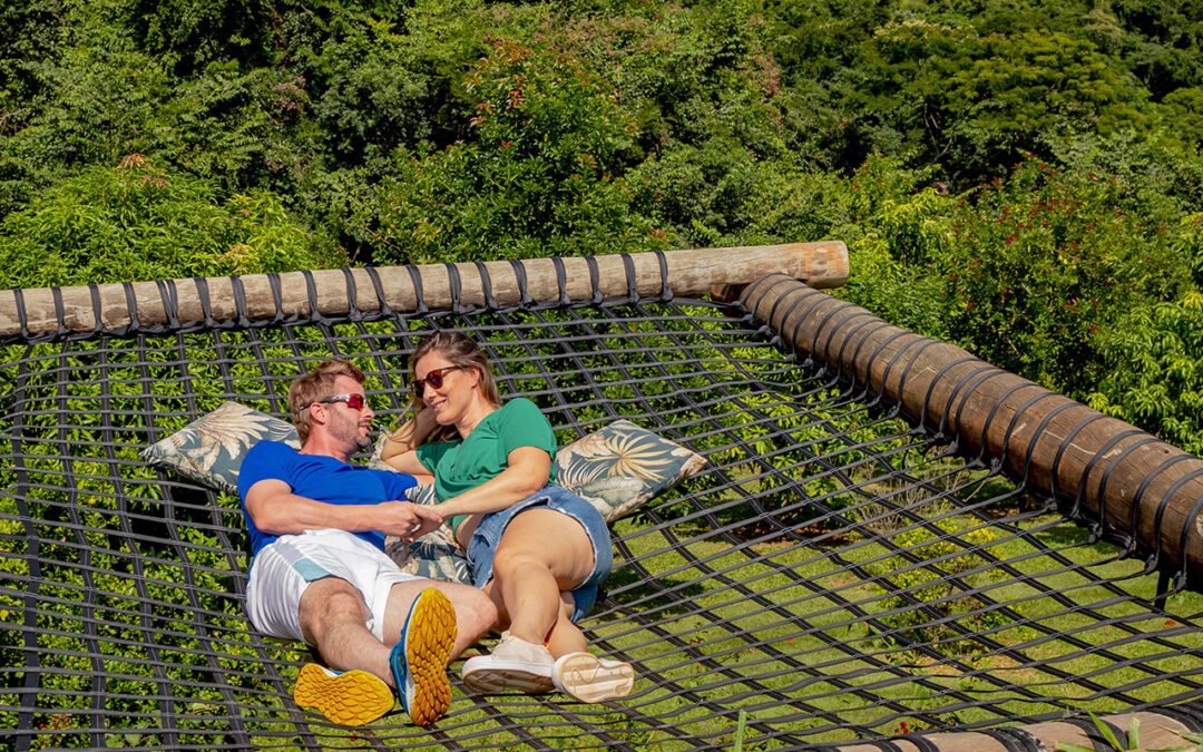 Casal descansando na rede suspensa entre as árvores