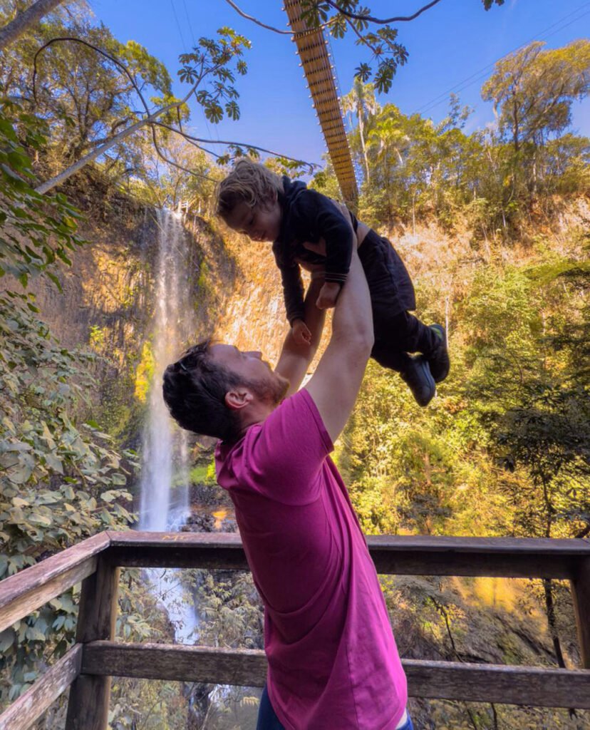 Pai brincando com o filho em frente a uma cachoeira no Cassorova