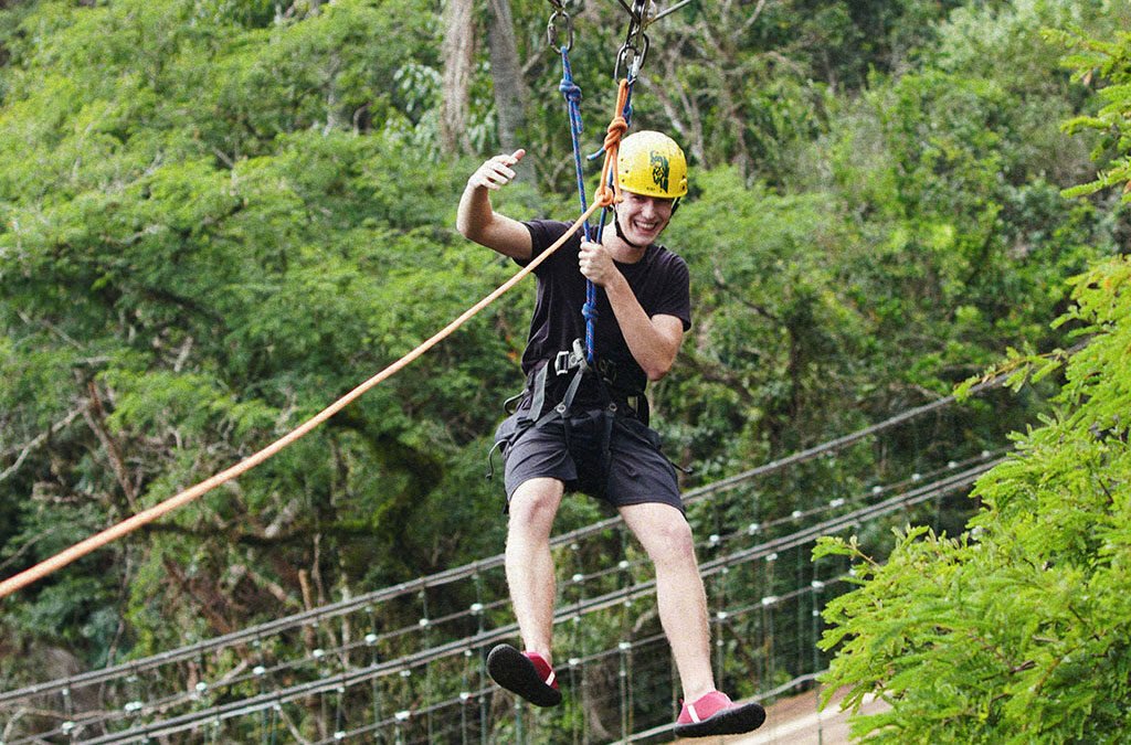 Criança de capacete atravessando o circuito de arvorismo